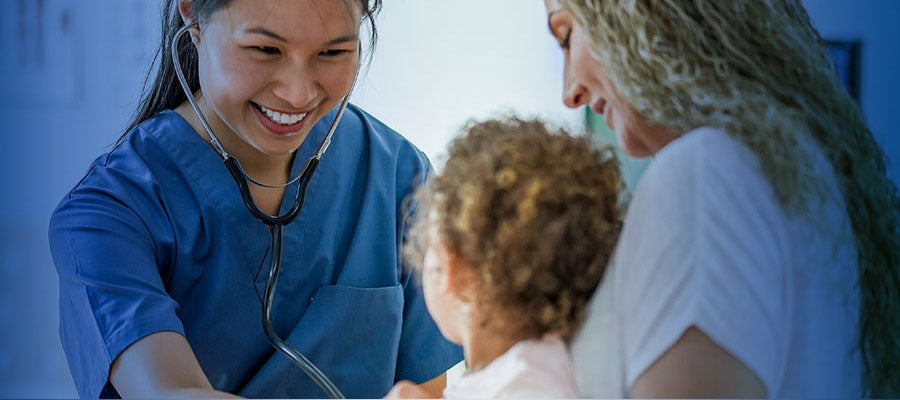nurse smiling at child in mother's arms