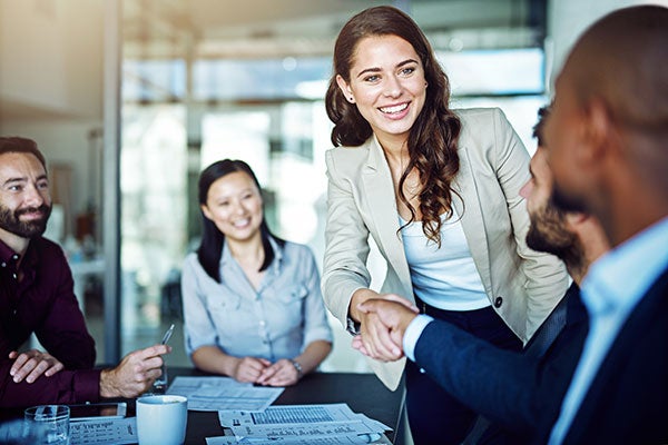 Woman shaking hands with people in background