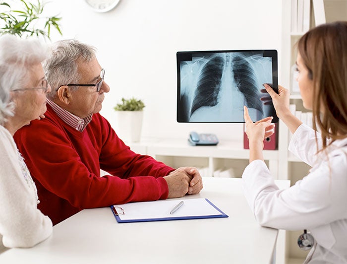 older adult woman and man looking at xray with doctor
