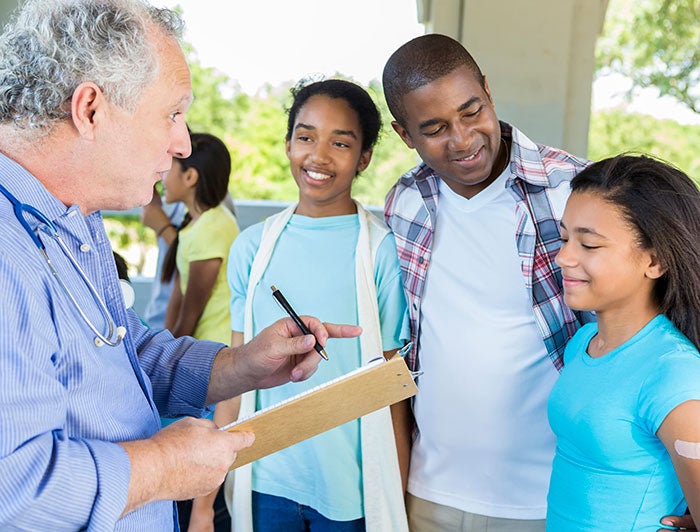 doctor talking to family at outdoor clinic