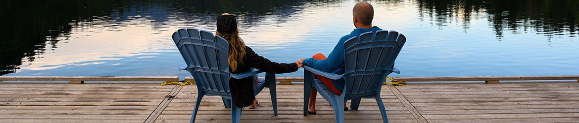 couple sitting on pier by lake