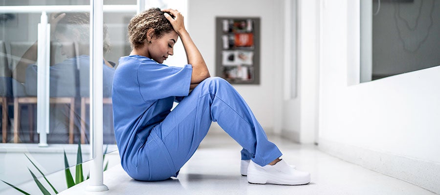 nurse sitting on the floor with head in hand