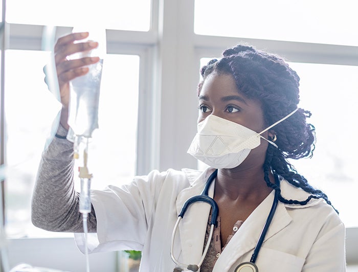 Nurse with mask on holding and IV drip