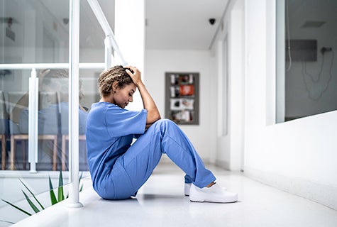stock photo of health worker on hospital floor with head in hands