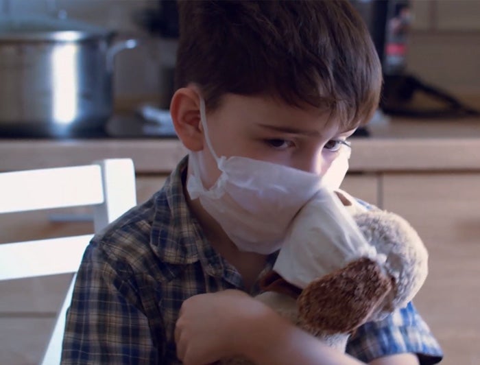 Boy with mask holding a plush puppy with a mask on