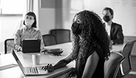 People at conference table spaced with masks