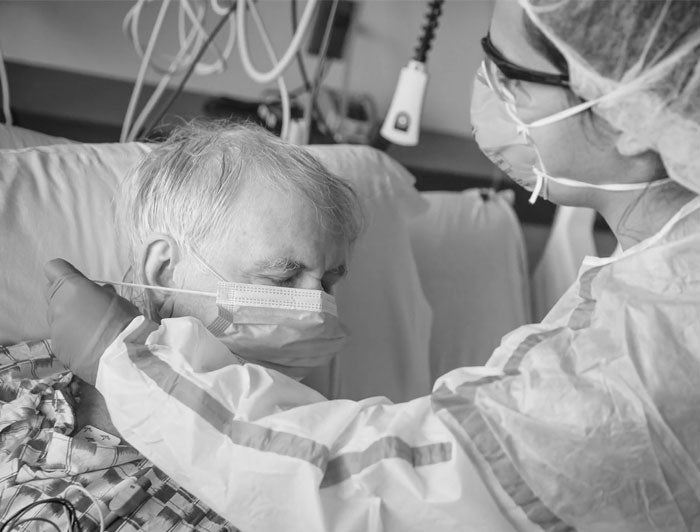 Nurse putting mask on elderly patient in bed