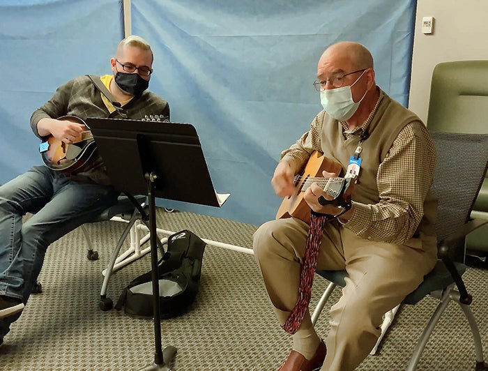Rick Lewis, M.D., plays guitar for patients at the Mary Washington vaccine clinic.