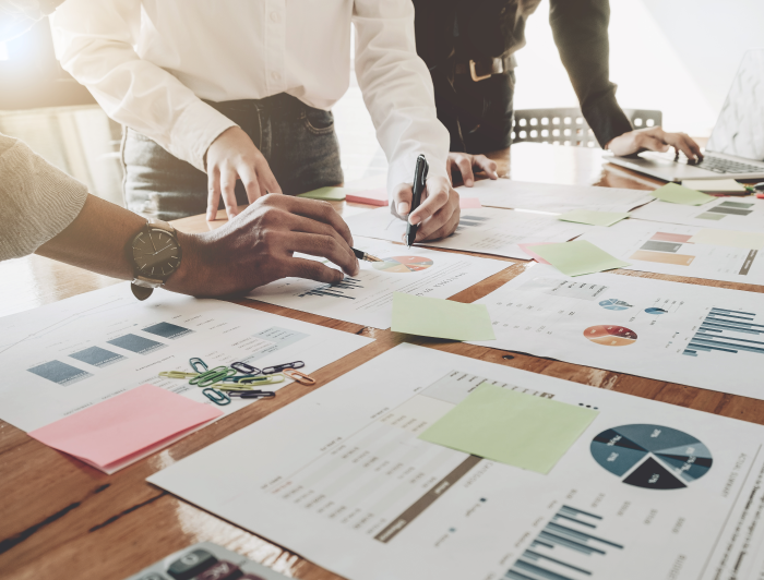 People analyzing graphs and documents spread out on table