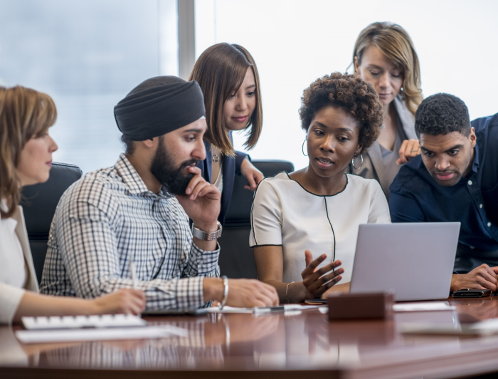 People looking at computer on conference table