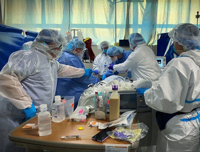 CoxHealth workers in full PPE gather around a sick patient in the COVID-19 unit