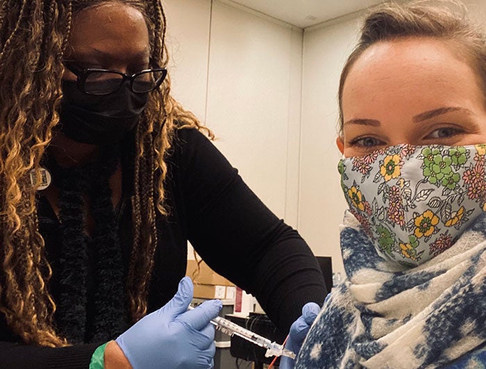 Caitlin Sutton, wearing mask receives vaccine from female Texas Childrens health worker