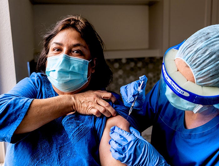 Female patient is vaccinated by a health worker in PPE