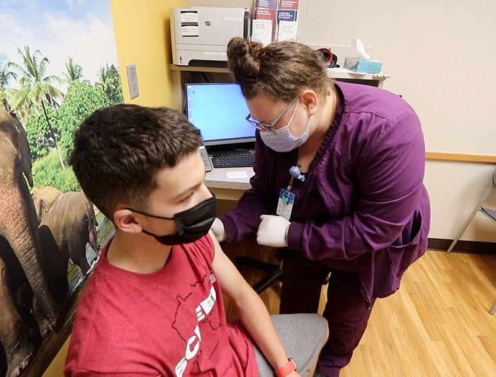 CentraCare health worker vaccinates adolescent boy