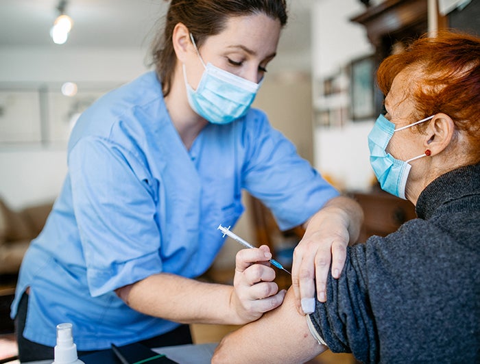 Female patient is vaccinated by a health worker in PPE