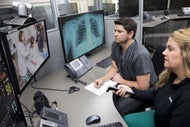 In Wake of Spinoff, Avera Health Plans to Keep Innovating. Two clinicians sitting at a shared desk watch on a monitor as a remote clinician examines a patient via Avera's telehealth platform..