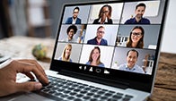 stock image of a group of nine smiling people on a video call, displayed on a laptop screen