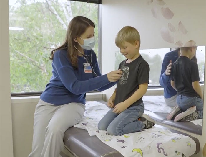 Health worker listens to boy's heart