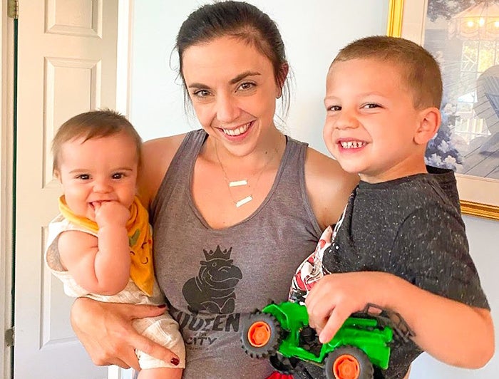 Smiling woman holds a child on each hip