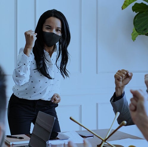 Fist pumping women in meeting with mask on