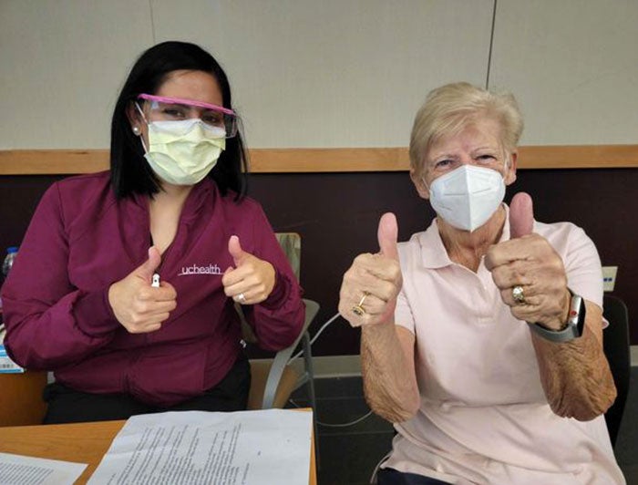 Two women,one a UCHealth worker and the other an elderly patient, give double thumbs up to camera