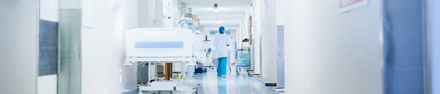 Medical staff walking down a long hallway with a gurney