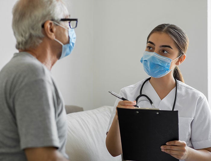 Nurse writing down information on notepad while talking with patient.