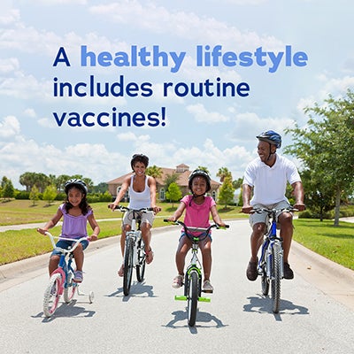 A smiling family of four rides bikes down a suburban street