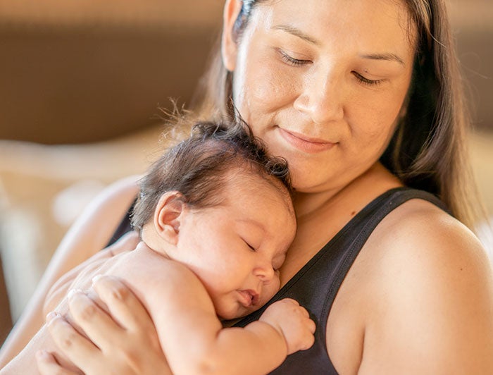 Woman with long hair holding her baby close to her chest