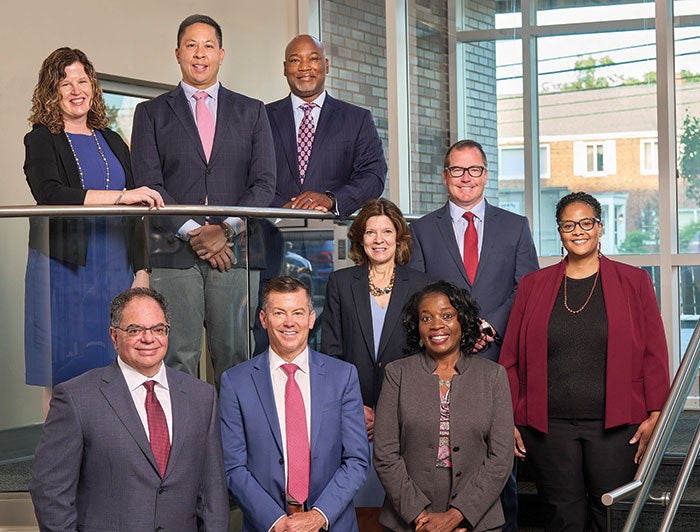 Representatives of the university hospital  dressed professionally, standing on the staircase of a building and posing for a professional picture