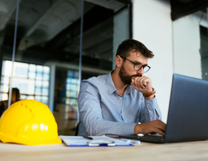 Person working at a desk with a hard hat on the table - Ventilation e-Learning Course