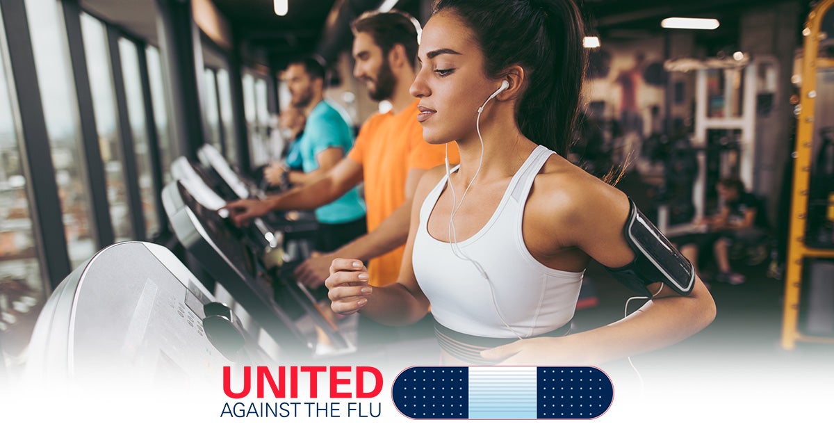 united against the flu - men and women exercise on a row of treadmills at a gym