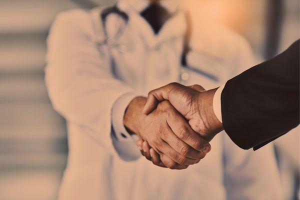 doctor shaking hands with businessperson