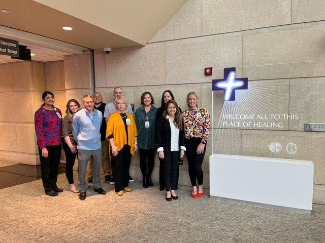 Staff of Advocate Condell Hospital standing next to a sign that says, "Welcome all to this place of healing."