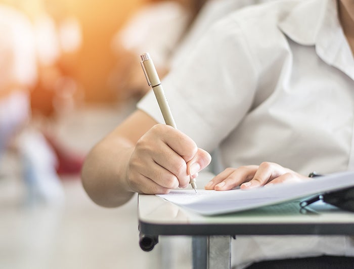 student seated at desk writing exam