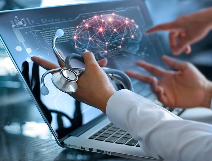 stock image of doctor hands gesturing at laptop showing brain image 