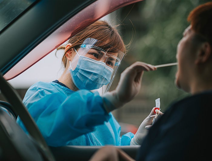 Medical person swabbing a person in a car