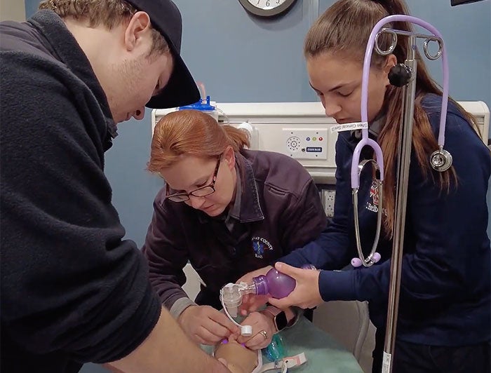 Three health workers train on simulator