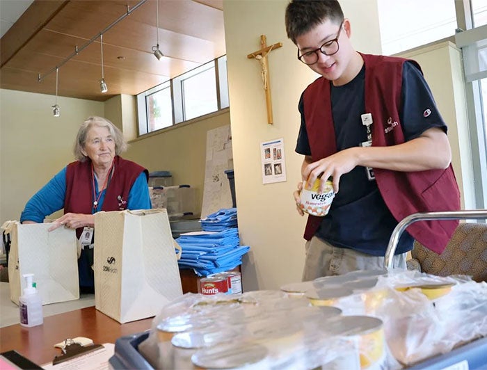 A young male and older female staffer fill grocery bags for new mothers