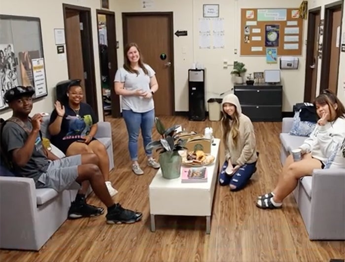 five smiling, diverse teens gathered in teen health center