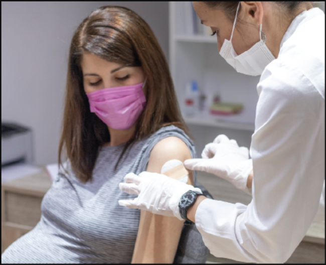 Pregnant female receiving a bandage on her arm after COVID-19 shot