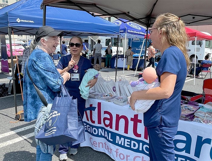 An older adult visitor stops by the Atlanticare fair to talk with health workers