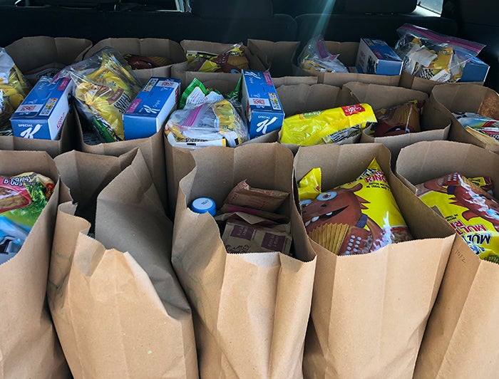 Filled grocery bags stand lined up at a food pantry