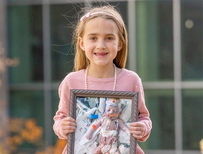 Havana holds up a photo of herself as a baby in the ICU