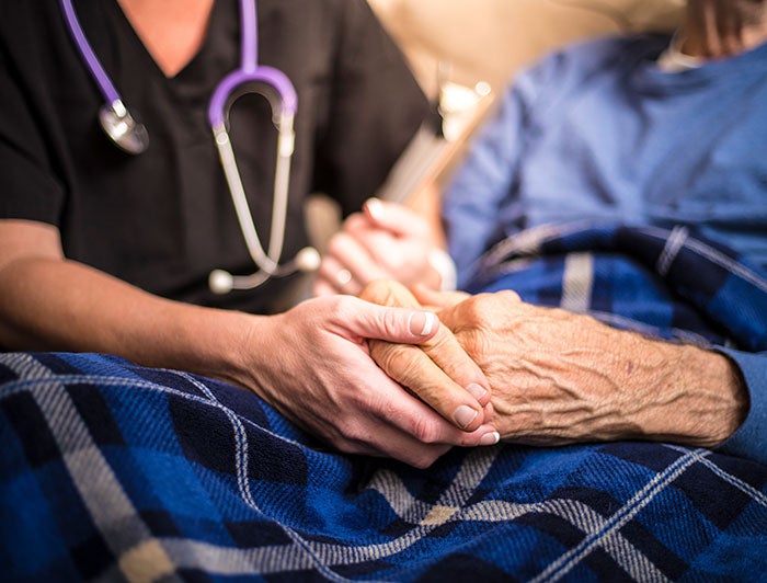 stock photo: health worker holds hands of elderly patient, their clasped hands the focus