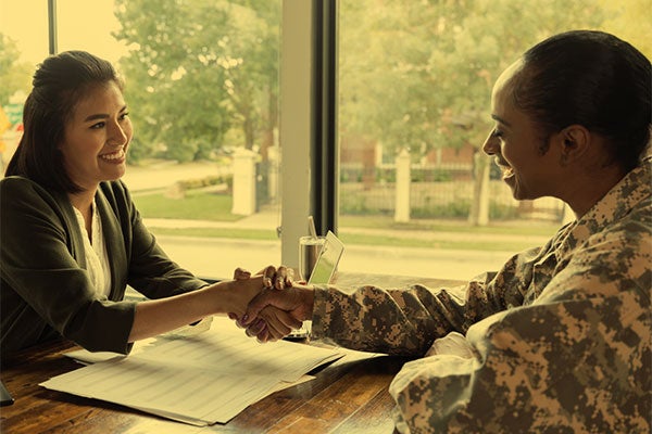 a female recruiter shakes hands with a female military applicant.
