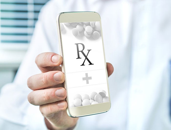 Rosebud eCare Telemedicine. Stock photo of a clinician's hands holding a smart phone bearning an app screen with Rx and pills on it