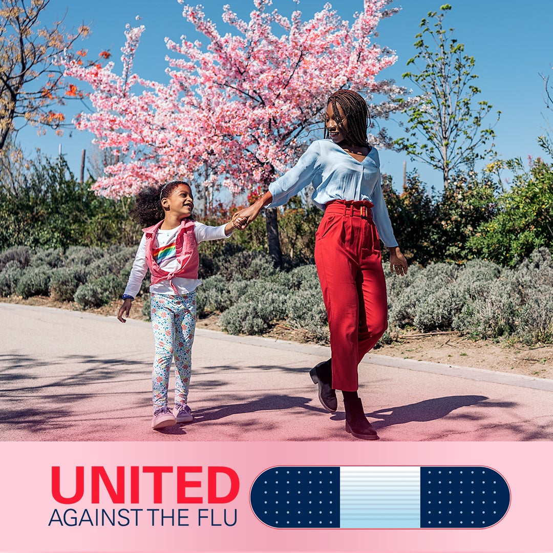united against the flu logo below image of Mother and daughter strolling hand in hand down a path with cherry tree blossoming in background
