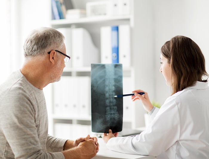 Stock image of female clinician, right, showing spine xray to male patient, left.