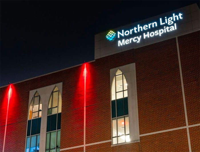 Telling the Hospital Story: Northern Light Health. Hospital exterior lit by red lights